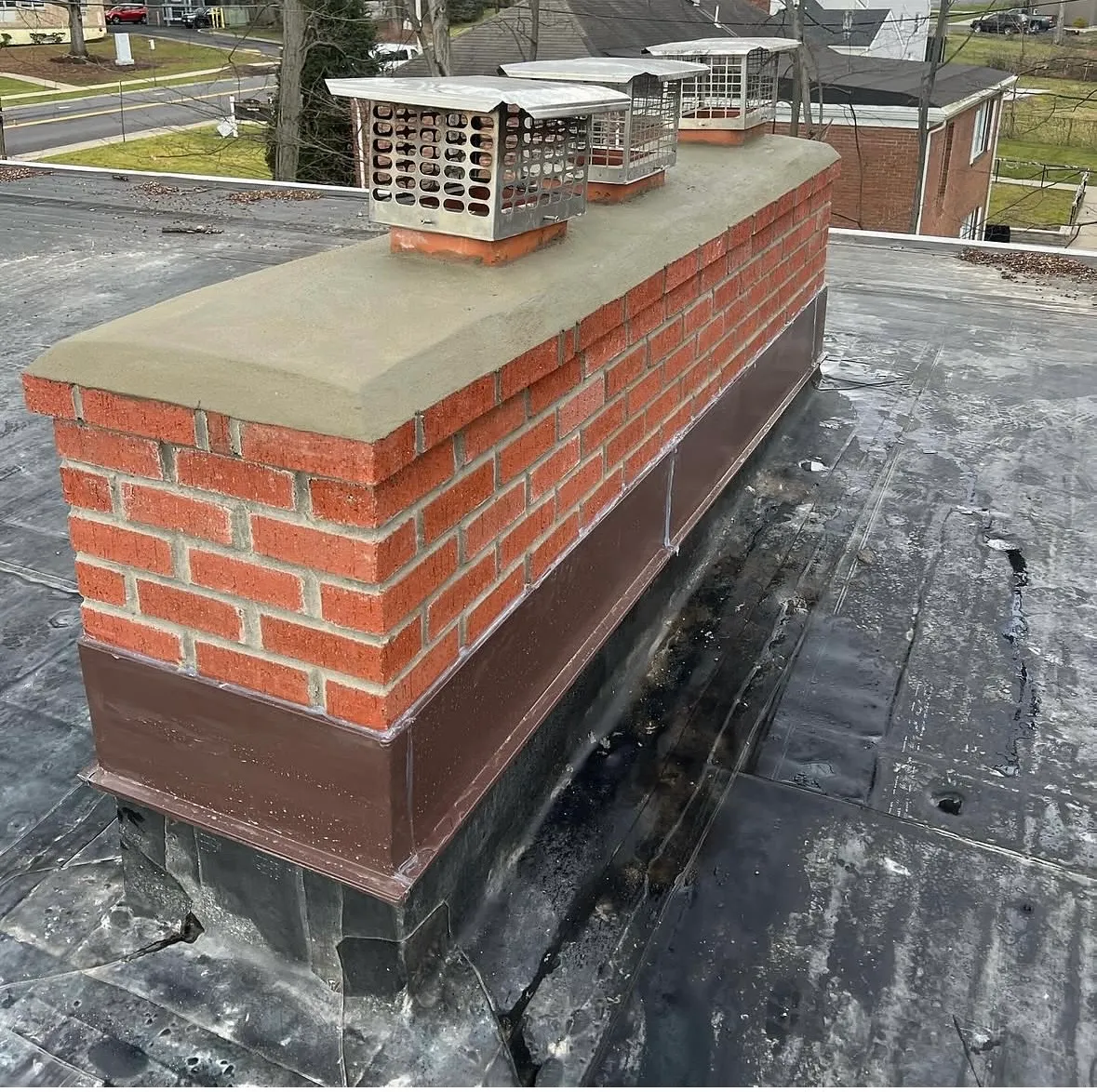 After: restored chimney in Pompton Plains NJ with new beveled concrete crown, repointed brick, new metal counter-flashing and stainless caps