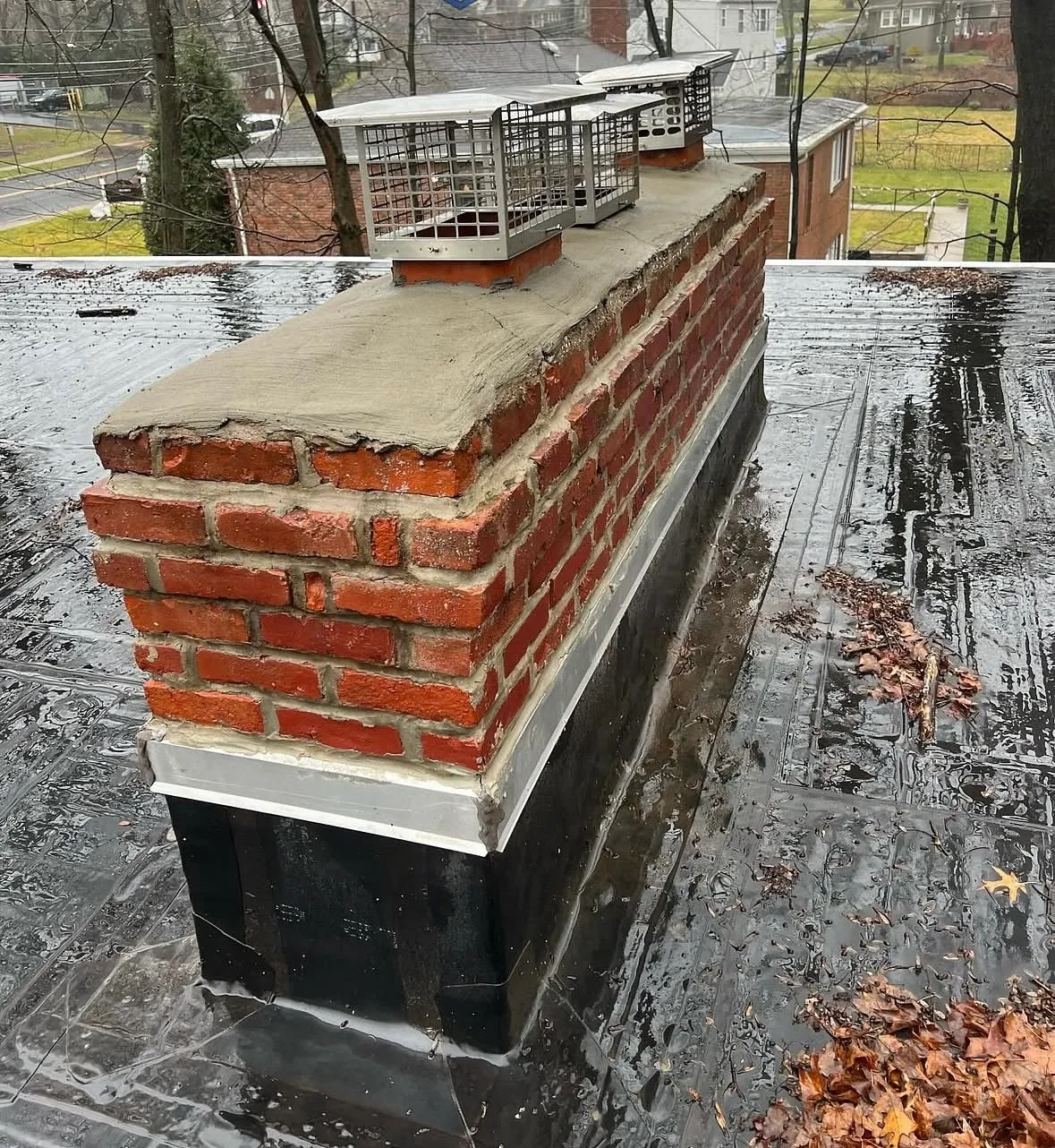 Before: chimney in Pompton Plains NJ with cracked crumbling crown and worn mortar joints on a flat roof
