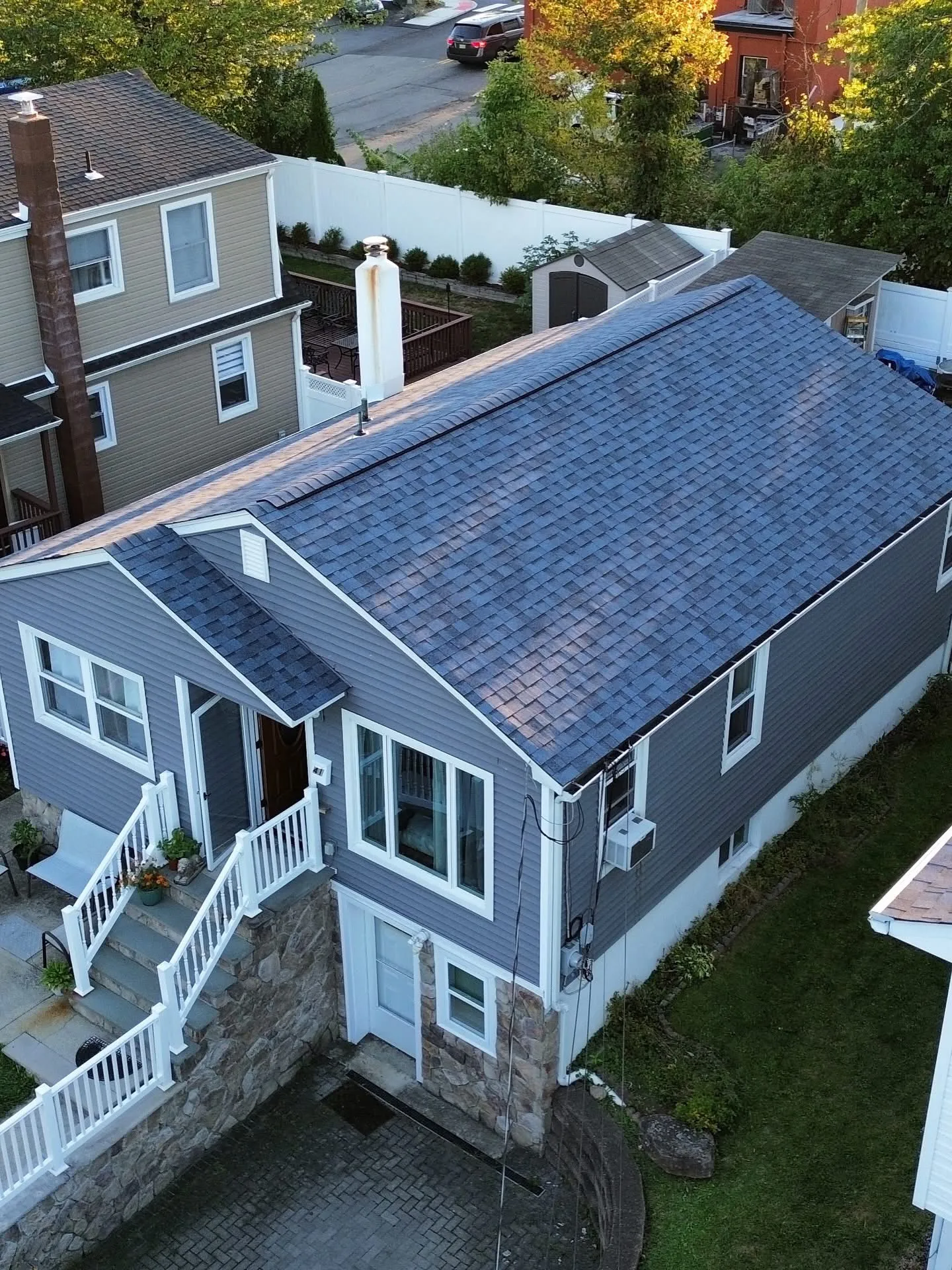 Drone view of a new gray shingle roof on a bi-level home with fresh white gutters